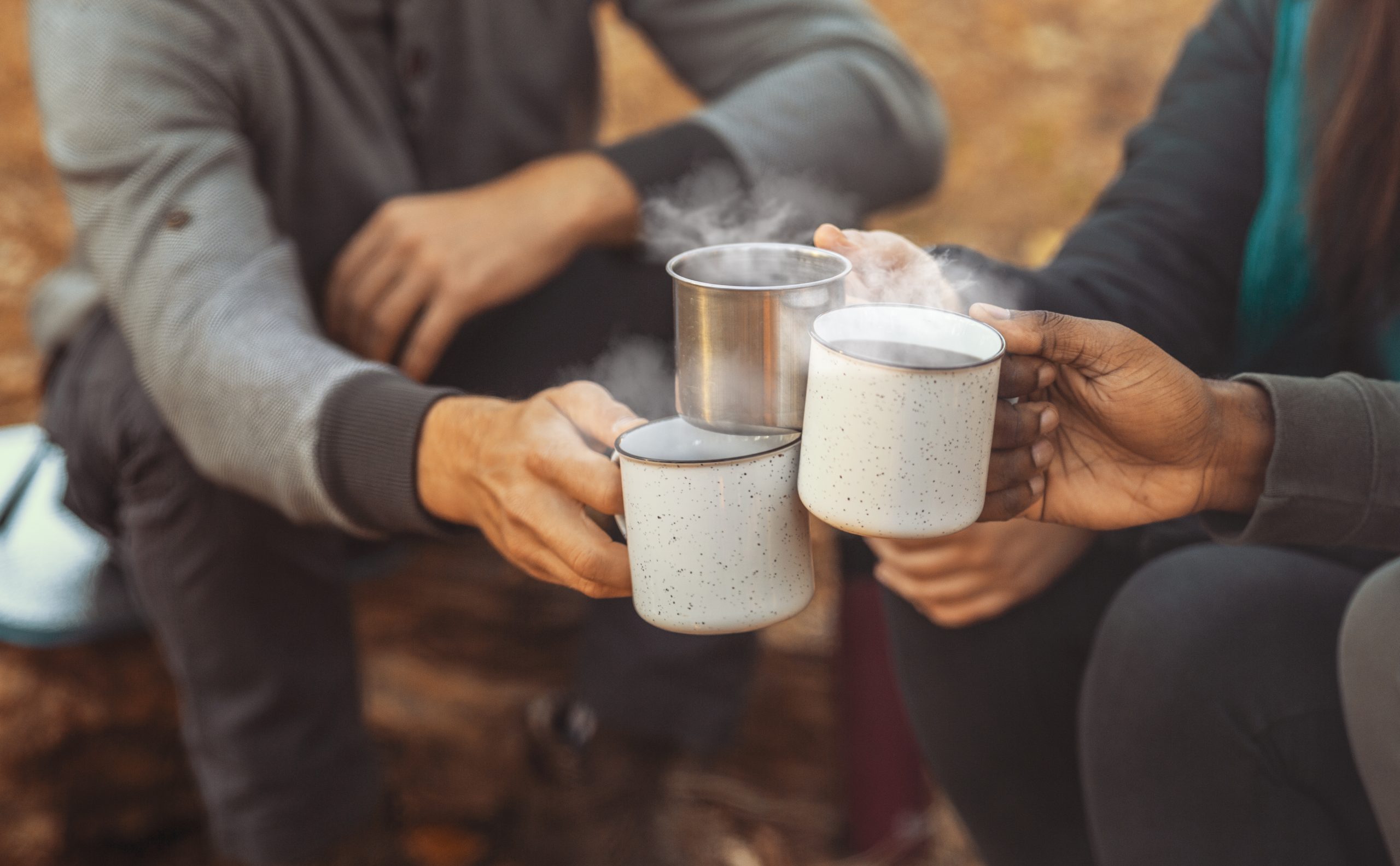 Hands of hikers cheering up with camping cups